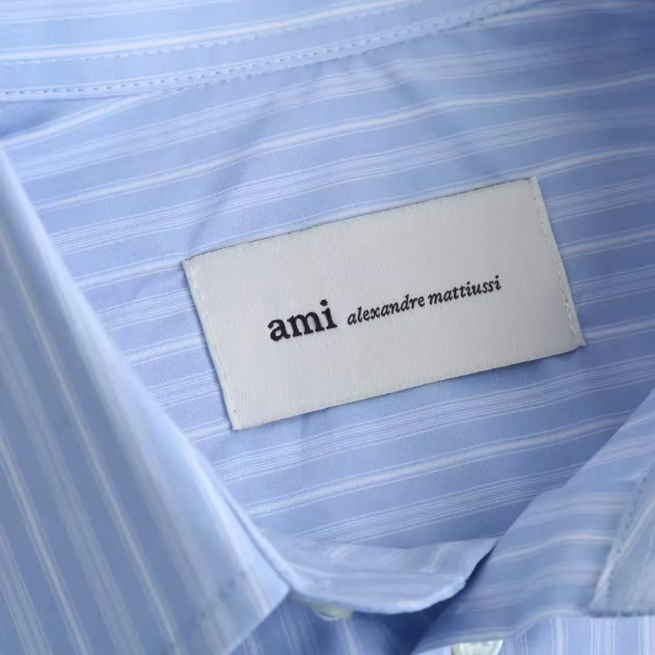 AMI Embroidered Striped Shirt Fabric Selection: Made of 100% cotton poplin fabric. The pure cotton fiber can quickly absorb moisture and perspire, making it refreshing and not stuffy when worn for a long time. The unique plain weave process of poplin makes the fabric both soft and skeletal, not easy to wrinkle and deform, and the upper body is neat and clean. Coupled with the fine blue and white stripes all over the body, the light color scheme is gentle and elegant, which can meet the needs of different scenes. Process 1: Accurately mark the embroidery position on the chest patch pocket to ensure that the pattern does not shift and does not destroy the overall beauty of the striped fabric. High-count embroidery threads of the same color as the fabric are selected, and flat stitch embroidery technology is used. The stitches are evenly tracked, the edges are clean and neat, and the love outline is simple and smooth. It retains recognition without irritating the skin. It is blended into the striped texture in a low-key manner to avoid an abrupt feeling, while ensuring that the embroidery threads are Wear-Resistant. 2: After the embroidery is completed, perform high-temperature ironing and thread trimming to ensure that the pattern is smooth and compliant, and it is not easy to lose thread or warp after being worn for a long time. Details: 1. The collar seat adopts double-layer reinforcement technology, which is not easy to collapse and deform after long-term wear. The collar corner has a soft arc, which can modify the neck line without being too sharp, making it neat and decent. 2. The inner side of the placket has hidden hemming treatment to avoid burrs on the fabric, while enhancing structural stability and preventing it from deforming after multiple washes. Accessories: One-to-one customized buttons Size: S M L XL Style number: D 236